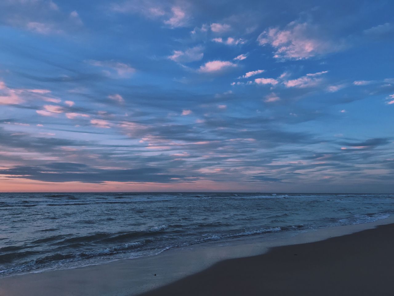 About Calm ocean waters and colorful sky at sunset on De Haan beach, Belgium.